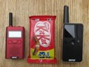 Tiny CP183 and CP228 walkie-talkies next to a KitKat bar