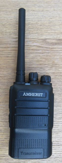 The Amherst A66 Compact Walkie-Talkie is a black handheld radio with two control knobs and an aerial, labelled "AMHERST" and shown on a wooden surface.