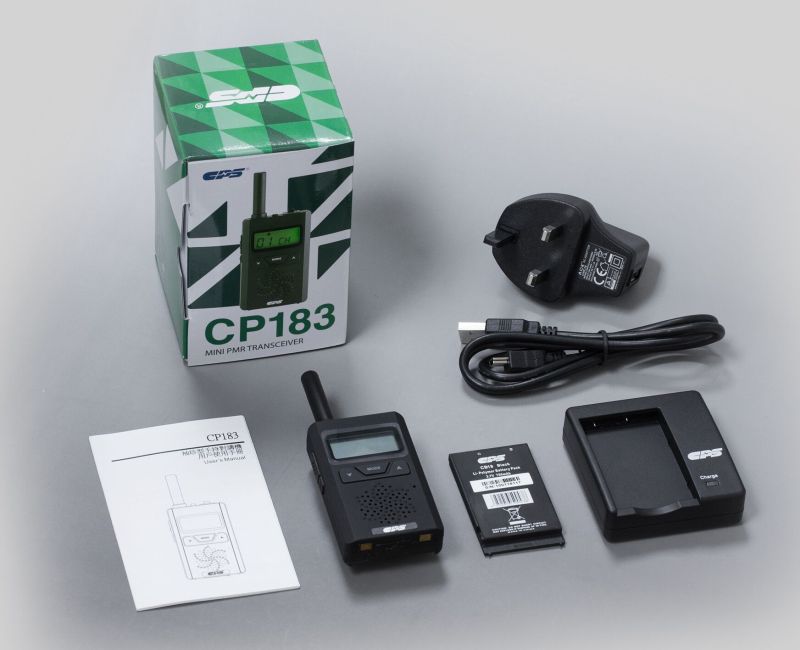 The CPS Telecom CP183 Tiny PMR446 Radio, its battery, charging dock, power adaptor, USB cable, user manual, and product box are neatly arranged on a flat surface.