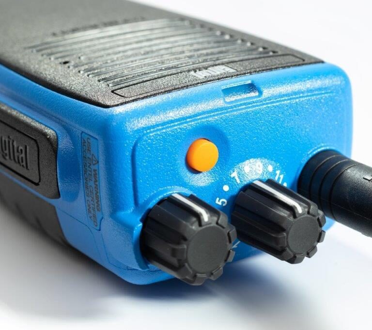 entel-dt982-close-up-1 Close-up of the Entel DT982 Atex 2c walkie-talkie in blue, featuring two black control knobs, an orange button, and part of its aerial.