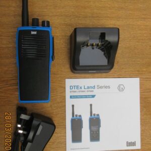 entel-dt982-what-you-get An Entel DT982 Atex 2c walkie-talkie in blue, with a charging dock, power adaptor, and DTE Ex Land Series quick start guide are displayed on a wooden surface.