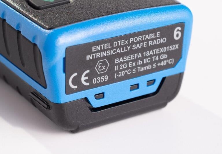 Close-up of a blue Entel DT985 Atex 2c display walkie-talkie showing technical and certification details on its label.