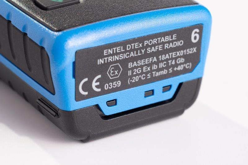 Close-up of a blue Entel DT985 Atex 2c display walkie-talkie showing technical and certification details on its label.
