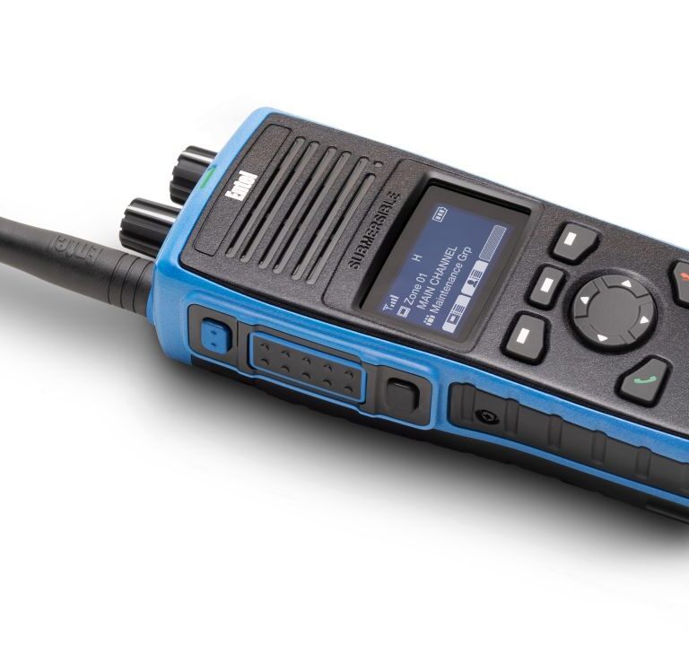 entel-dt985-front-side The Entel DT985 Atex 2c is a handheld walkie-talkie featuring a blue casing, aerial, display screen, and multiple control buttons.