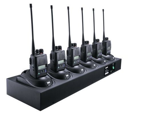 entel-hx-6-slot-charger Six handheld two-way radios are arranged in a row, each seated in the Entel HX/DX Six-slot charger CSBHX connected to a single charging station.