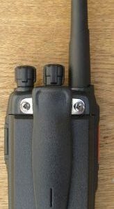 A Kirisun DP405 Digital / Analogue Two-Way Radio, featuring a black handheld design with an aerial and two knobs, is placed on a wooden surface.