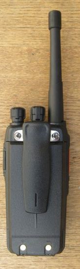 kirisun-dp405-walkie-talkie-back A Kirisun DP405 Digital / Analogue Two-Way Radio, featuring a black handheld design with an aerial and two knobs, is placed on a wooden surface.