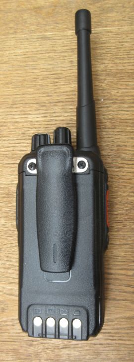 kirisun-dp480-back-view A black Kirisun DP480 Digital / Analogue Walkie-Talkie Radio with a long aerial, seen from the back, rests on a wooden surface.