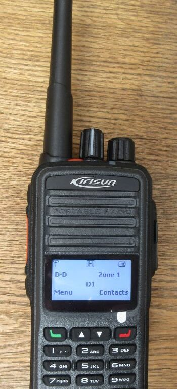 kirisun-dp480-walkie-talkie-screen-on A Kirisun DP480 Digital / Analogue Two-Way Radio with a display, keypad, and aerial sits on a wooden surface.