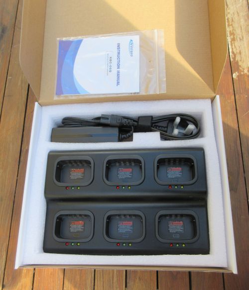 The Kirisun PT568 Six Slot Multi-Charger box includes a charging station with six battery slots and indicator lights, a power cable, an adaptor, and an instruction manual.