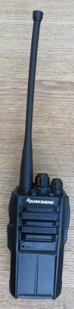 quansheng-tg-330-walkie-talkie-front-view A Quansheng TG330 Walkie Talkie Radio in black with a long aerial rests on a wooden surface.