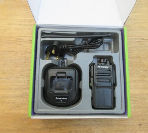 Box containing a Quansheng TG330 Walkie Talkie Radio, charging dock, plug, and aerial neatly arranged in moulded packaging on a wooden surface.
