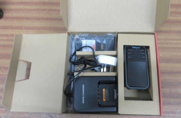talkpod-a50p-box-contents A cardboard box contains a black A50P UHF Mesh Walkie-Talkie, rapid charger, power adaptor, and leadโall packed in separate compartments.
