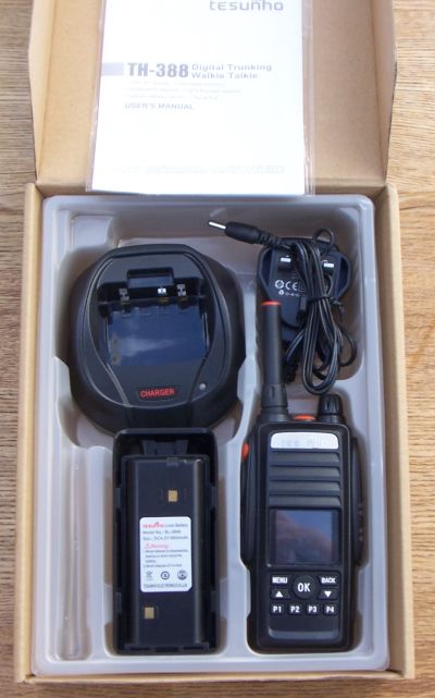 A Tesunho TH388 Display GPS Network Walkie Talkie Radio, charger, battery, and user manual are neatly arranged in a cardboard box.